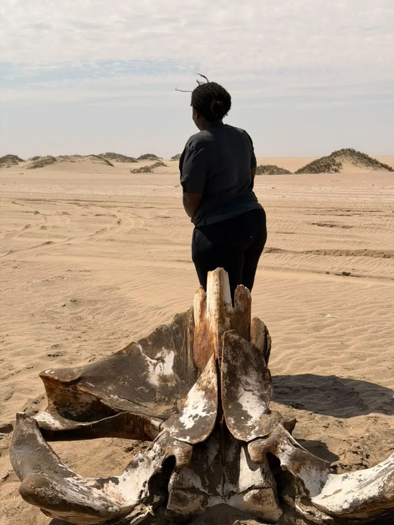 Irene exploring a sandy coastline, with whale bones in the foreground